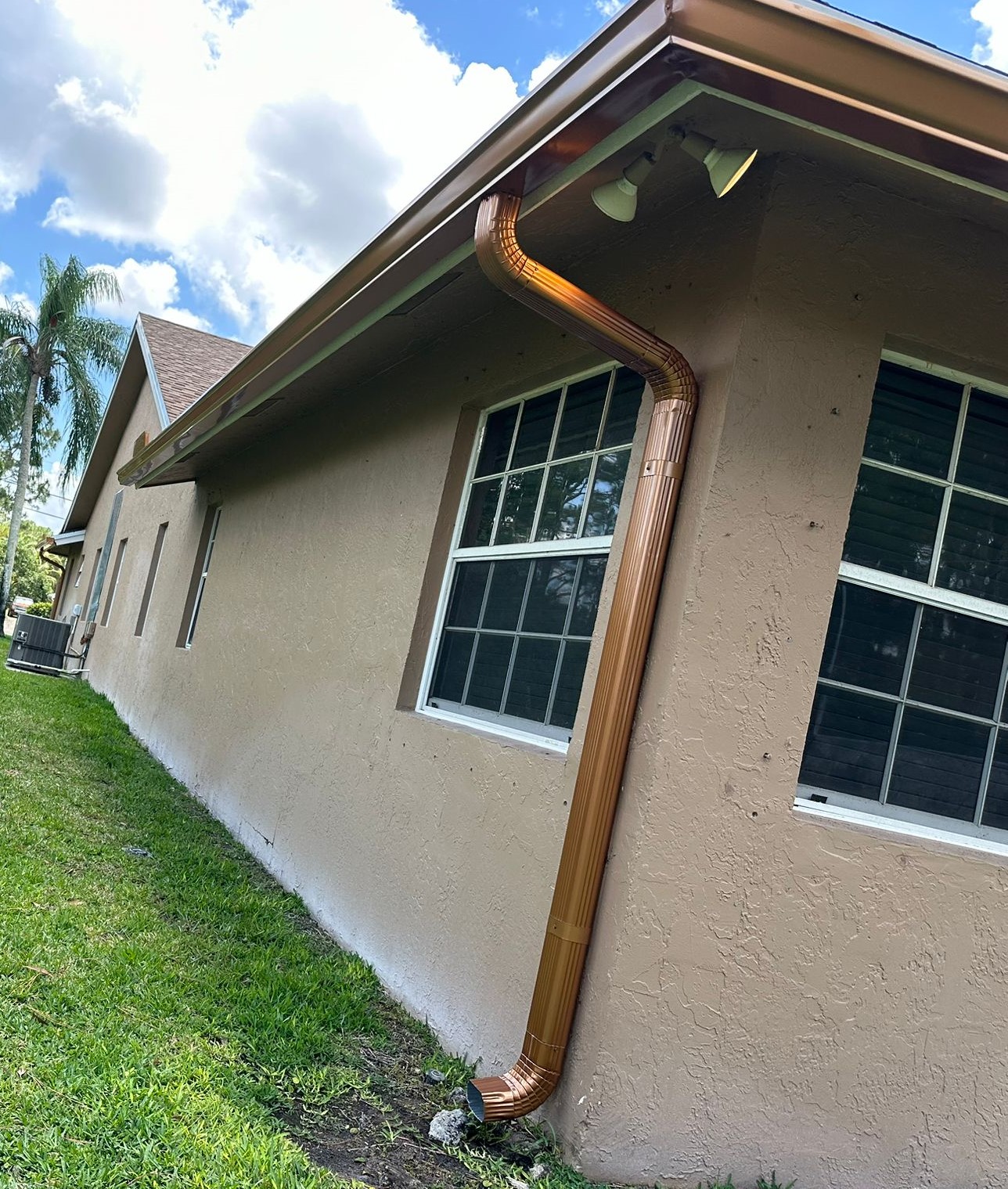 Grey stucco house exterior with new gutters by NK & Gutter